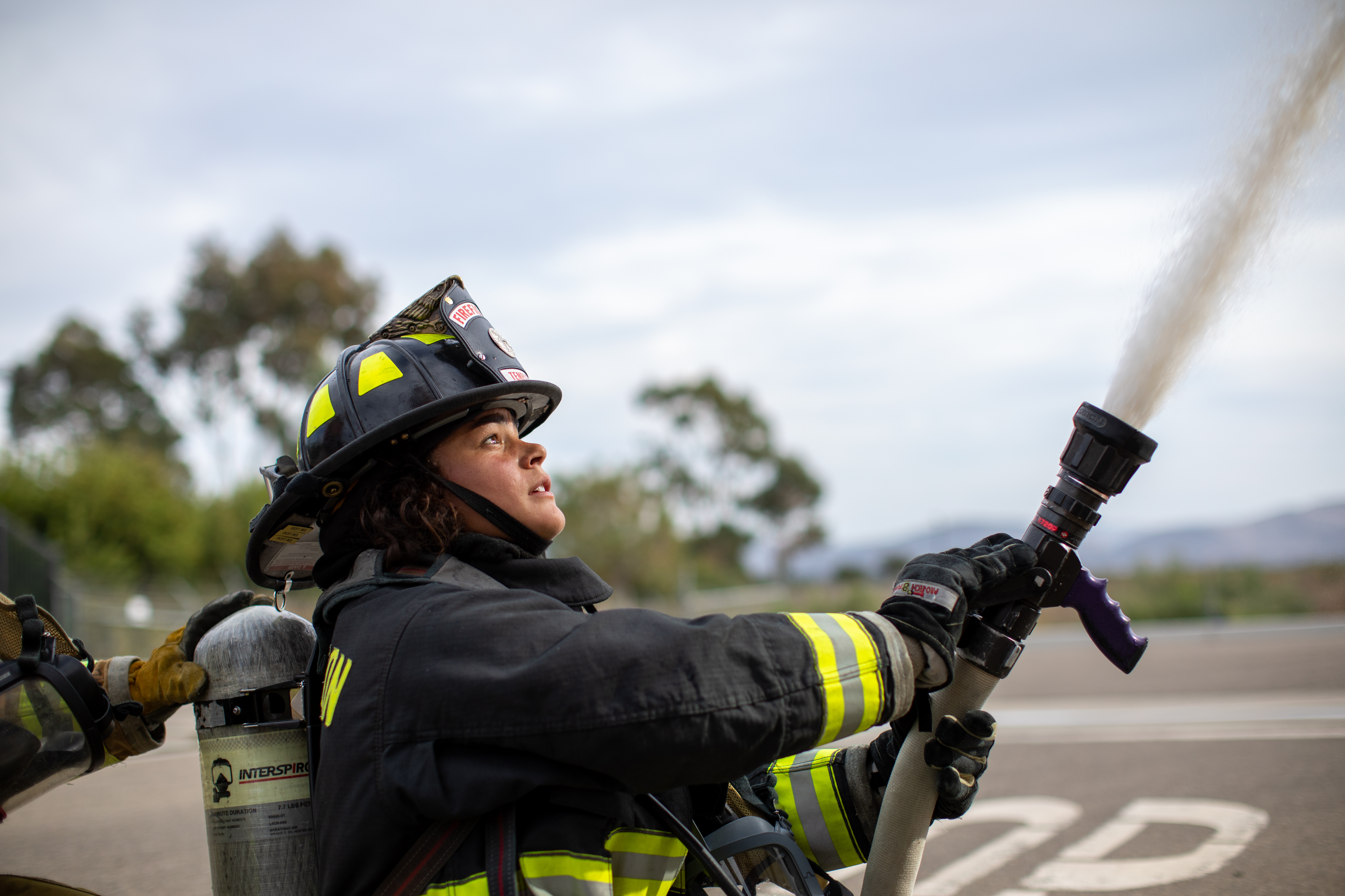 A female firefighter uses a hose.