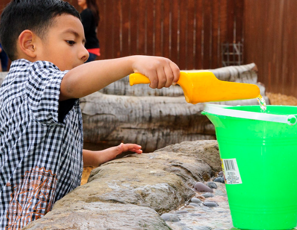Child pouring water into bucket