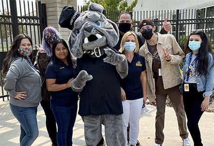 Group of people surrounding a bulldog mascot. 