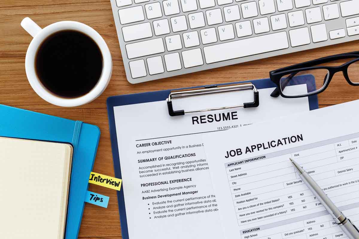 Closeup of job hunting materials on desk with keyboard and coffee
