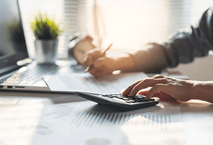 hands working at a desk with a calculator