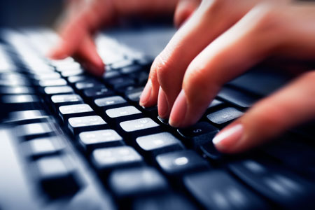 Hands typing on a computer keyboard