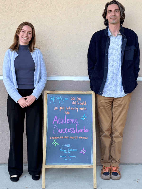 Sean Maddox and Kyra Golike standing and smiling on each side of a colorful welcome sign.