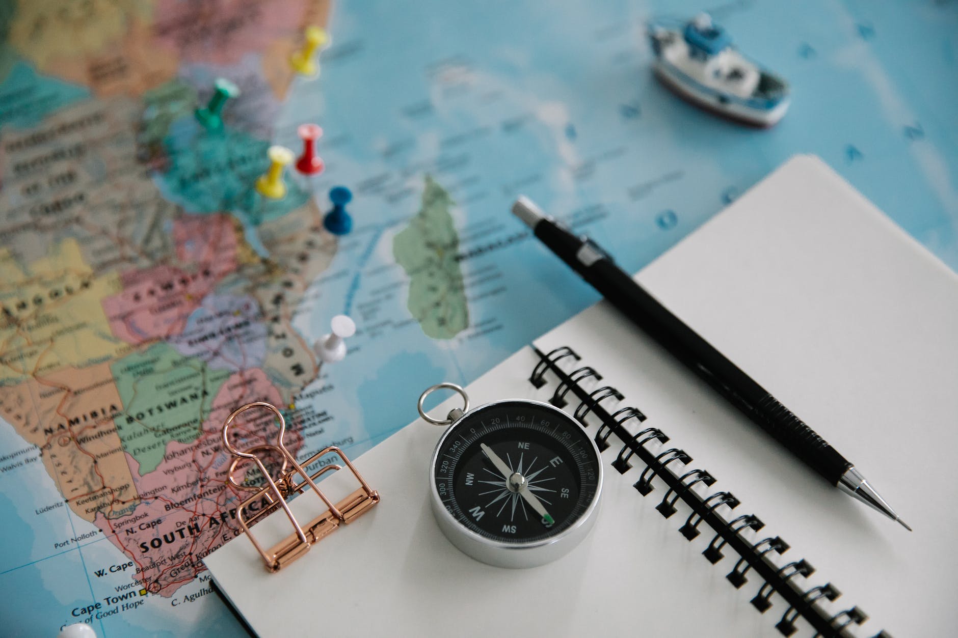 notebook and compass on top of a world map